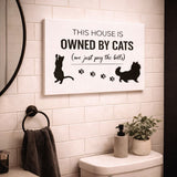 Owned By Cats canvas in White & Black hanging above a toilet in a tiled bathroom