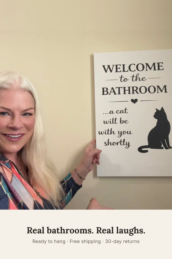 Woman smiling next to the funny cat bathroom canvas hanging on her wall