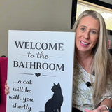 Woman holding the funny cat bathroom canvas - Welcome to the Bathroom, a cat will be with you shortly