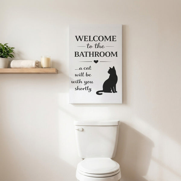 White Welcome to the Bathroom cat canvas hanging above a toilet