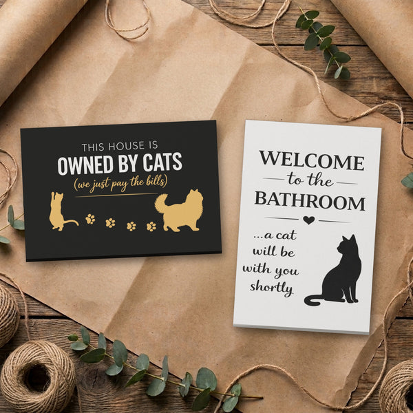 Cat canvas set, Bathroom and Black & Gold Owned By Cats, side by side on kraft paper