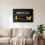 Black and gold This House Is Owned By Cats canvas above a living room sofa