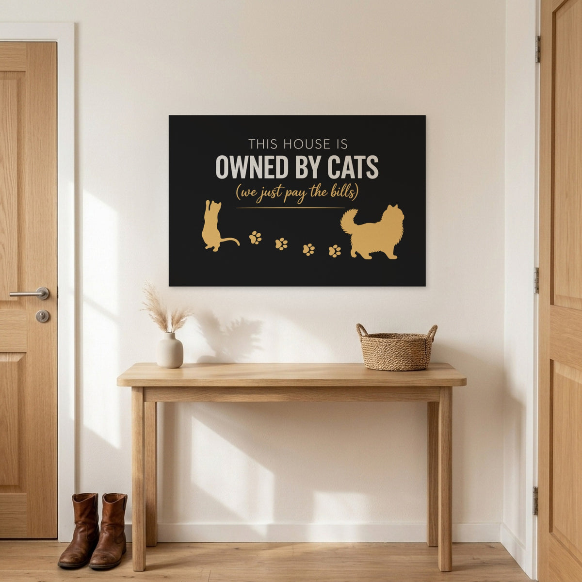 Black and gold This House Is Owned By Cats canvas above an entryway table