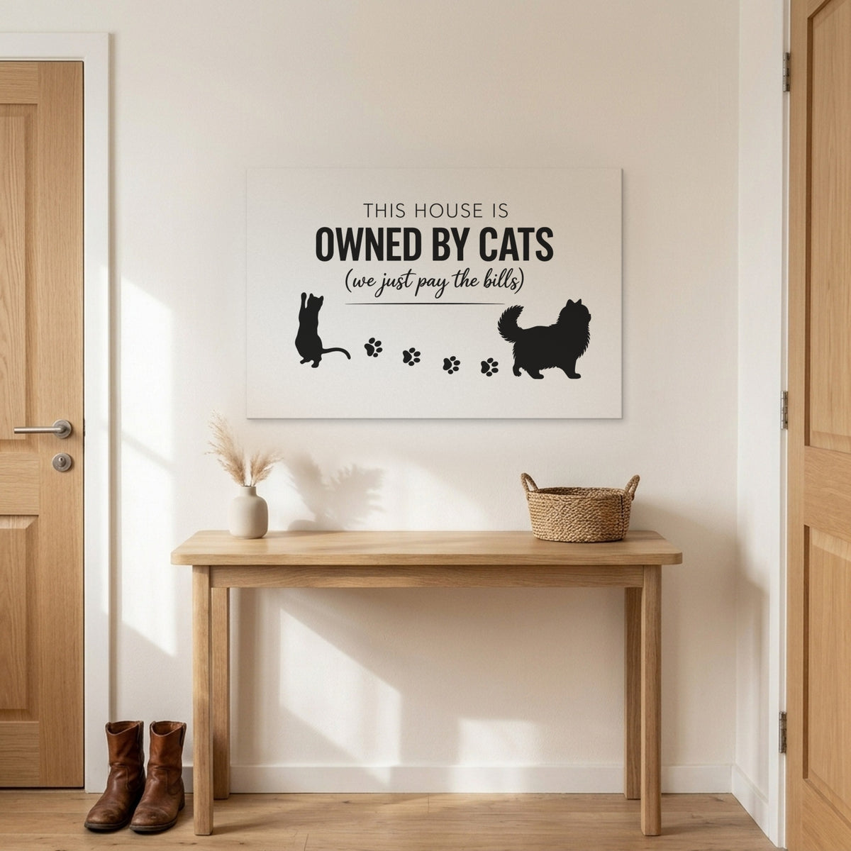 White and black This House Is Owned By Cats canvas above an entryway table