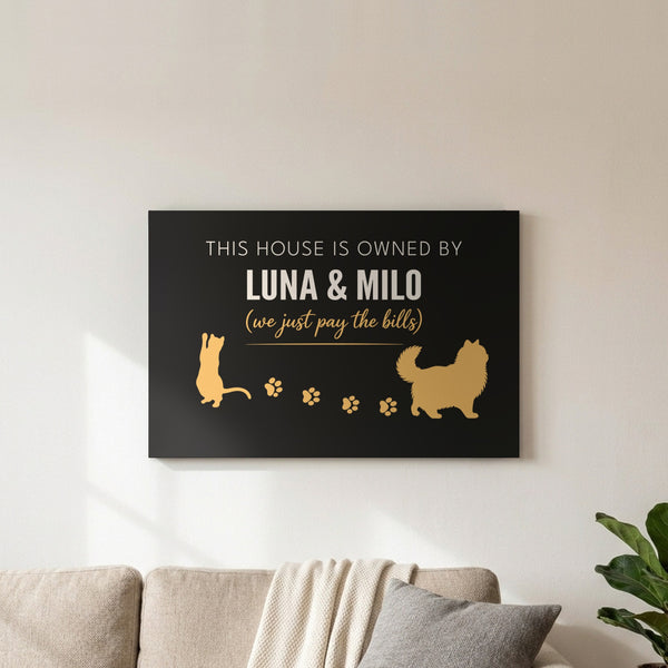Personalized Owned By Cats canvas, Black & Gold, reading This house is owned by Luna & Milo, above a living room sofa