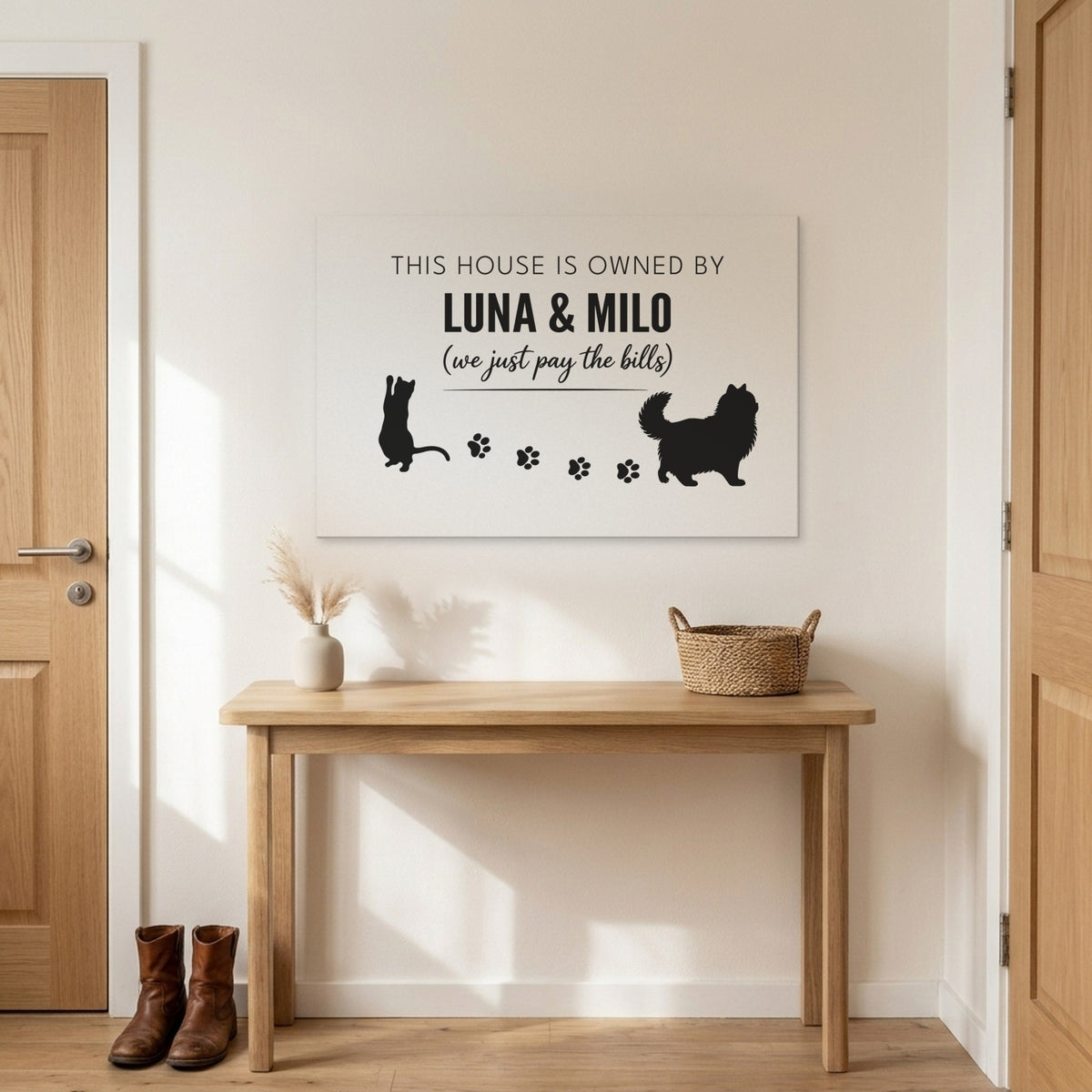 White and black This House Is Owned By Luna & Milo canvas above an entryway table