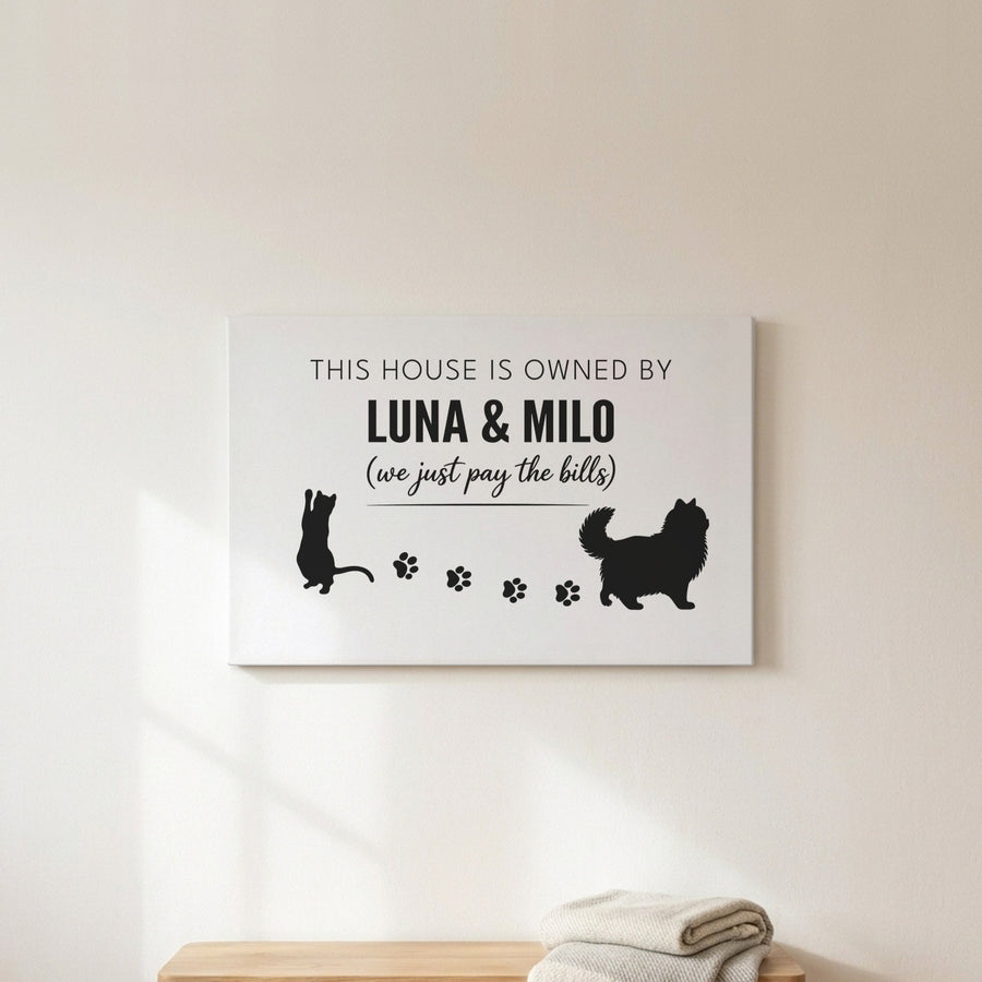 Personalized Owned By Cats canvas, White & Black, reading This house is owned by Luna & Milo, above a wooden bench