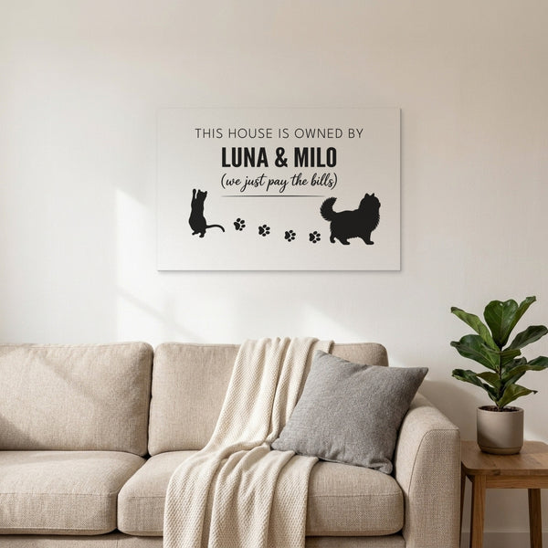 White personalized This House Is Owned By Luna & Milo canvas above a living room sofa